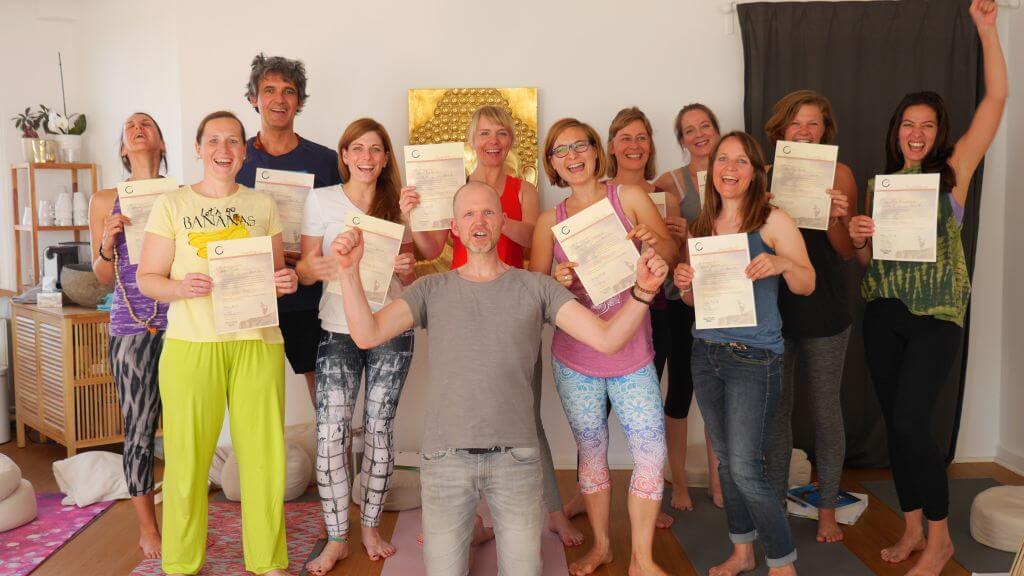 Stolze Teilnehmer der Yoga Ausbildung Köln halten Zertifikat hoch